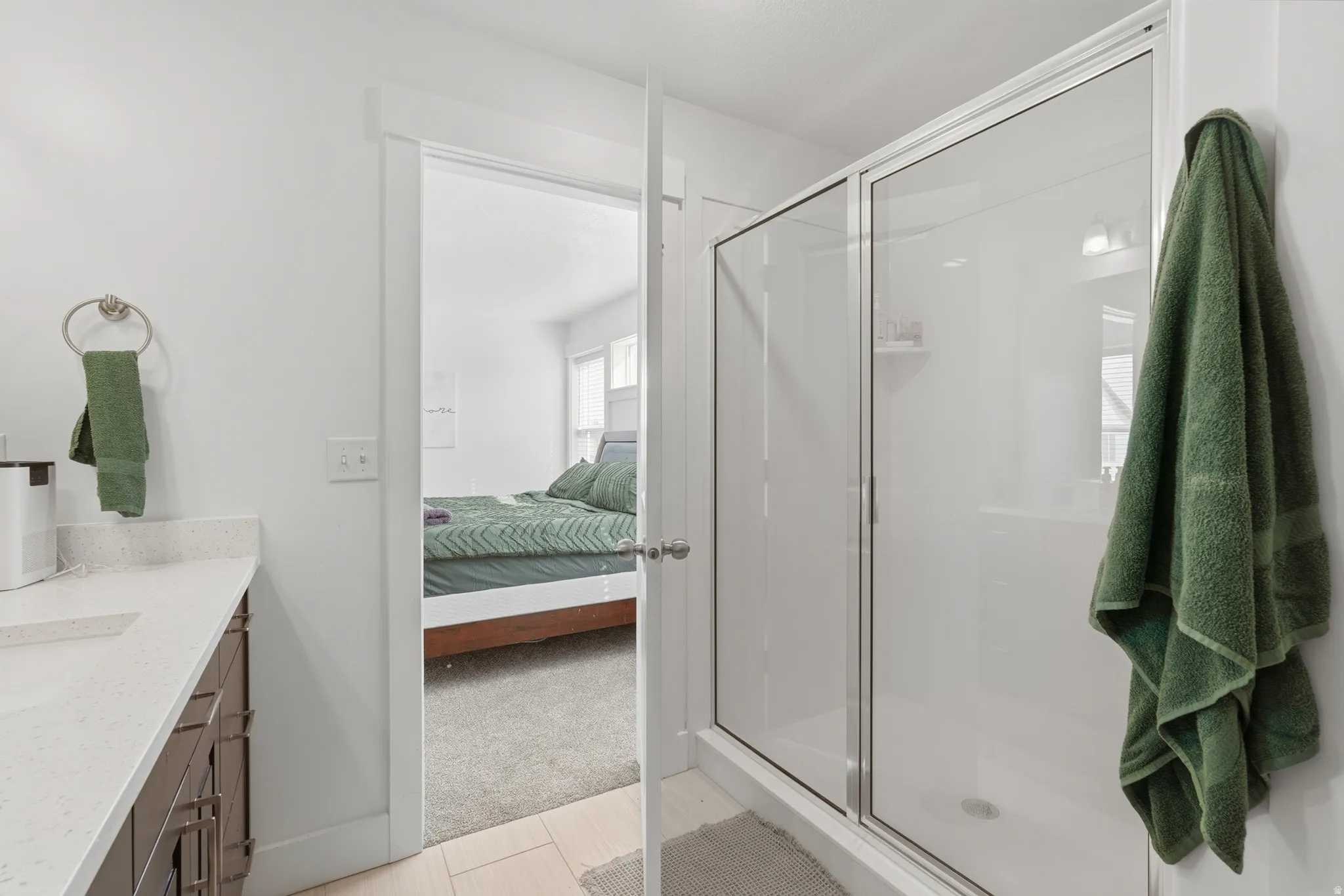 Ensuite bathroom with vanity, a stall shower, and light carpet