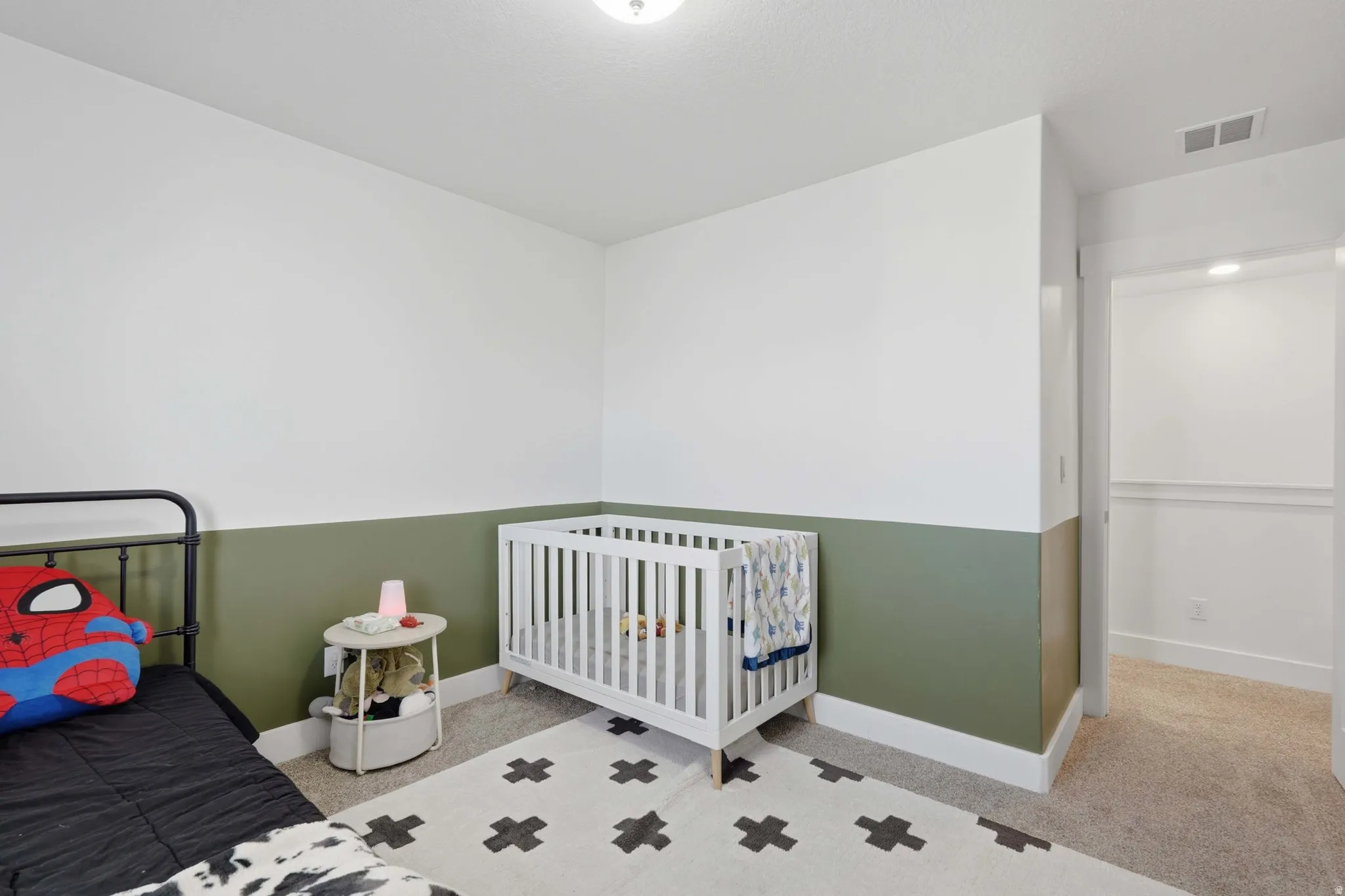 Bedroom featuring light carpet and a crib