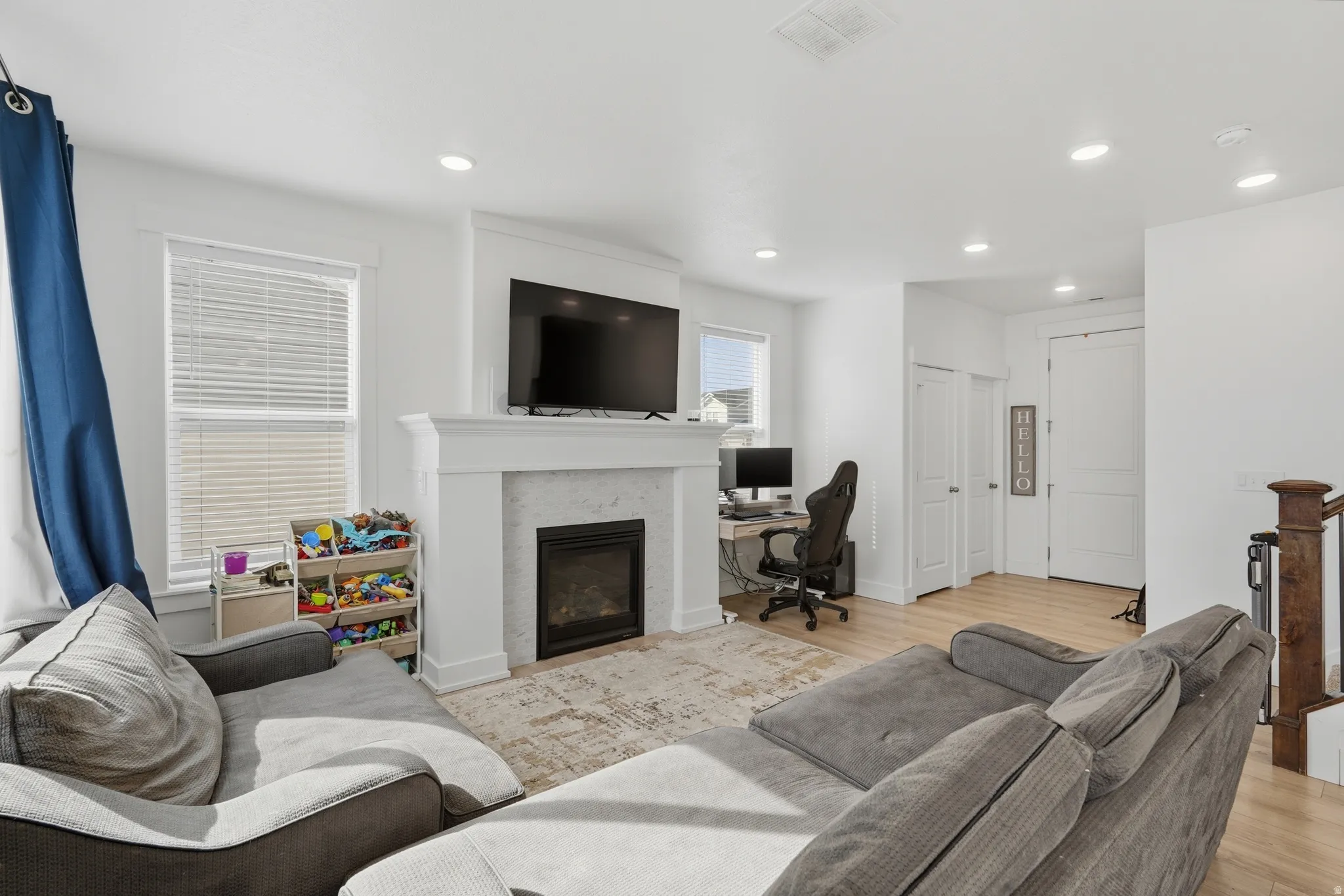 Living area featuring light wood-type flooring, a glass covered fireplace, an office area, and recessed lighting