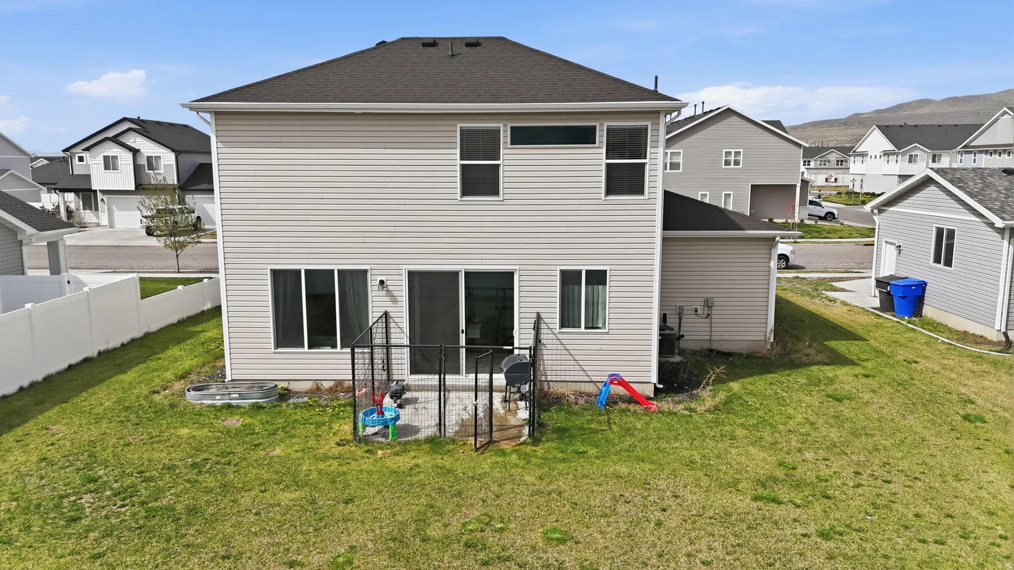Back of property featuring a residential view, a lawn, and roof with shingles