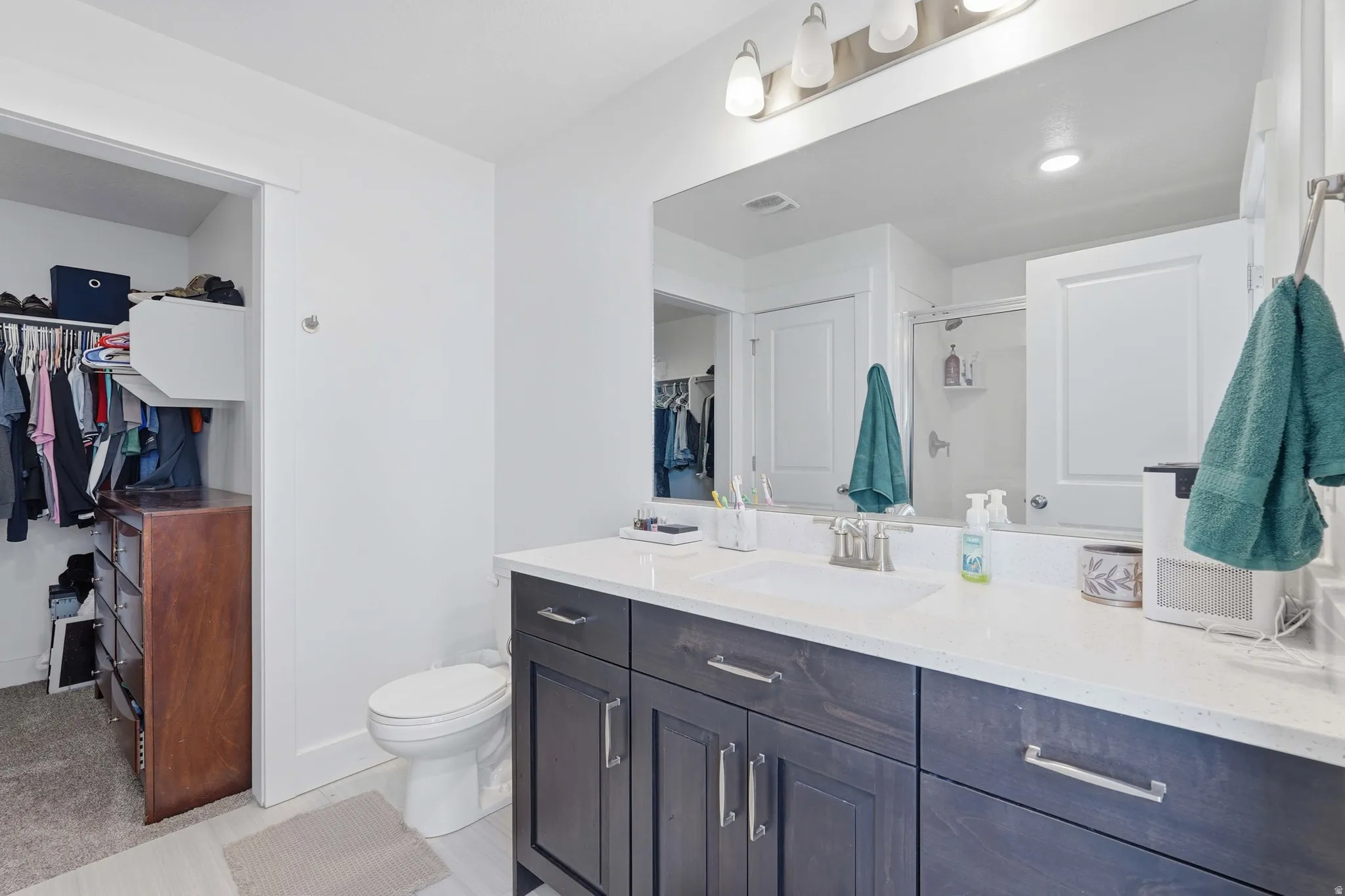 Full bathroom featuring a walk in closet, a stall shower, and vanity