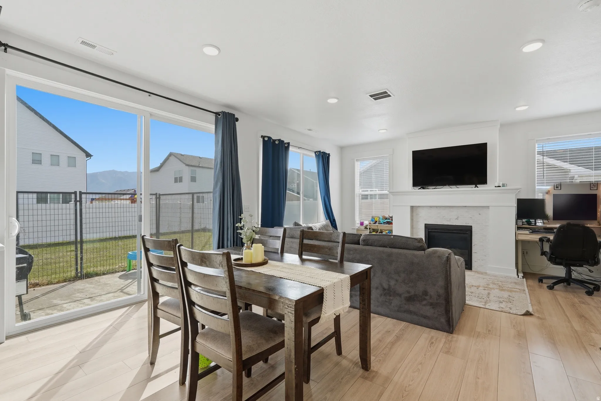 Dining space featuring a desk, light wood finished floors, plenty of natural light, a glass covered fireplace, and recessed lighting