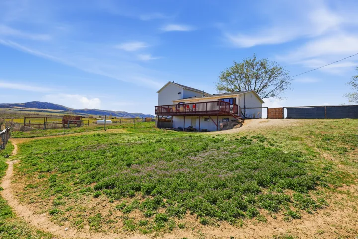 Rear view of property with a fenced backyard, a deck with mountain view, and a rural view