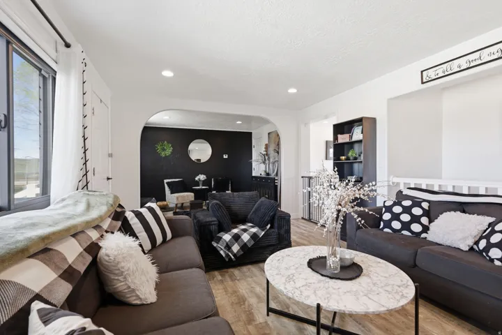 Living room with light wood-style flooring, arched walkways, and recessed lighting
