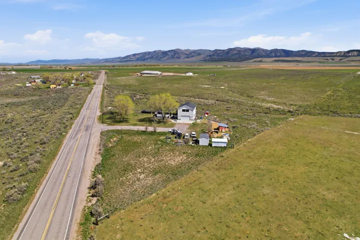 Aerial view of property and surrounding area featuring rural landscape and a mountainous background