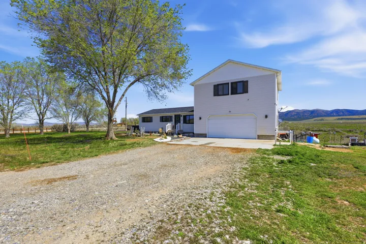 View of front of property featuring a garage, driveway, a patio, a front lawn, and a mountain view