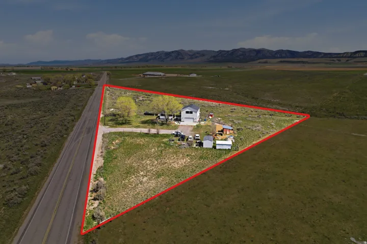 Aerial view of sparsely populated area featuring property boundaries highlighted and a mountainous background
