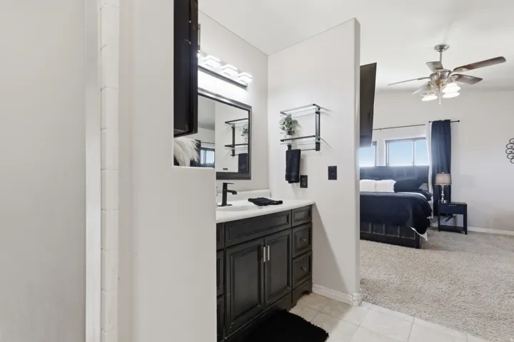 Bathroom featuring light carpet, vanity, ceiling fan, ensuite bath, and light tile patterned floors