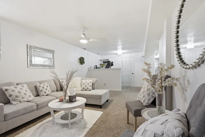 Living room with ceiling fan and light colored carpet