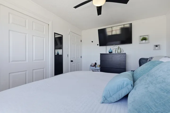 Bedroom with a textured ceiling, a ceiling fan, and crown molding