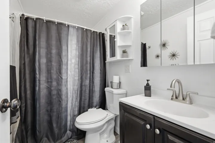 Bathroom with a textured ceiling, vanity, and curtained shower