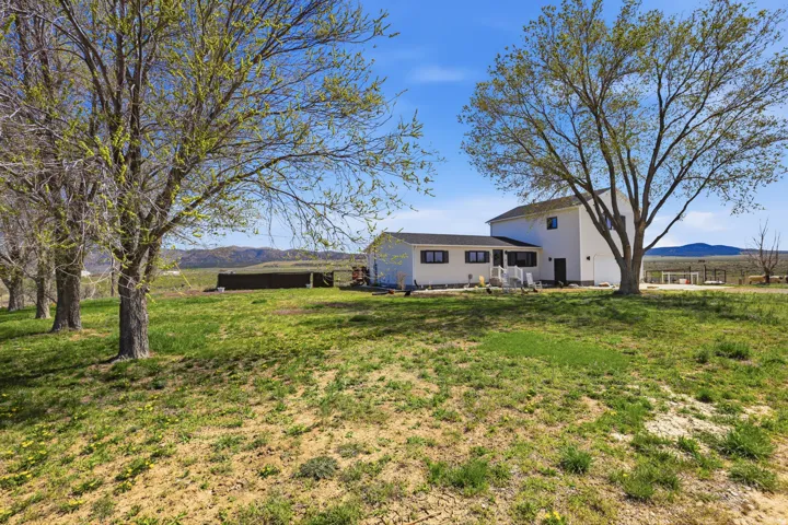 Back of property featuring a mountain view, a lawn, and a patio area