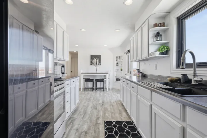 Kitchen featuring open shelves, white cabinets, dark countertops, stainless steel appliances, and recessed lighting