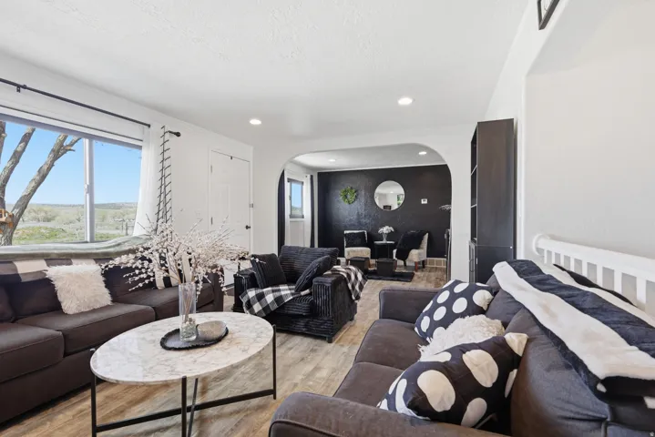 Living area featuring light wood-type flooring, arched walkways, ornamental molding, and recessed lighting