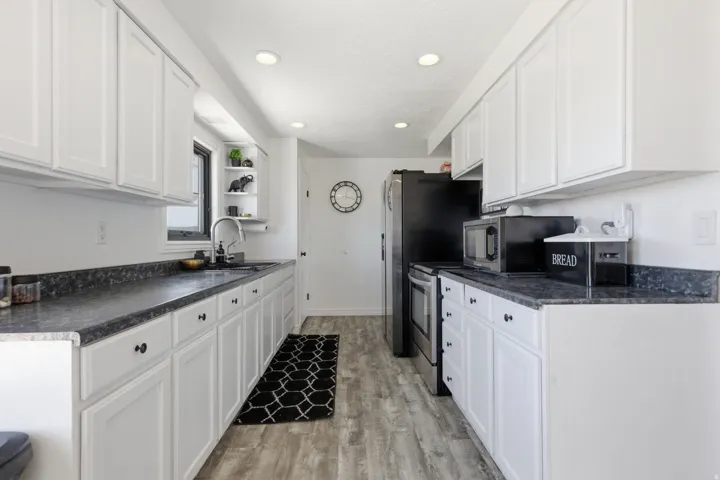 Kitchen with dark countertops, white cabinetry, open shelves, and recessed lighting
