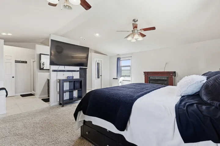 Bedroom with ceiling fan, vaulted ceiling, light colored carpet, recessed lighting, and ensuite bath