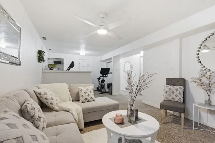 Carpeted living area featuring a ceiling fan and baseboards