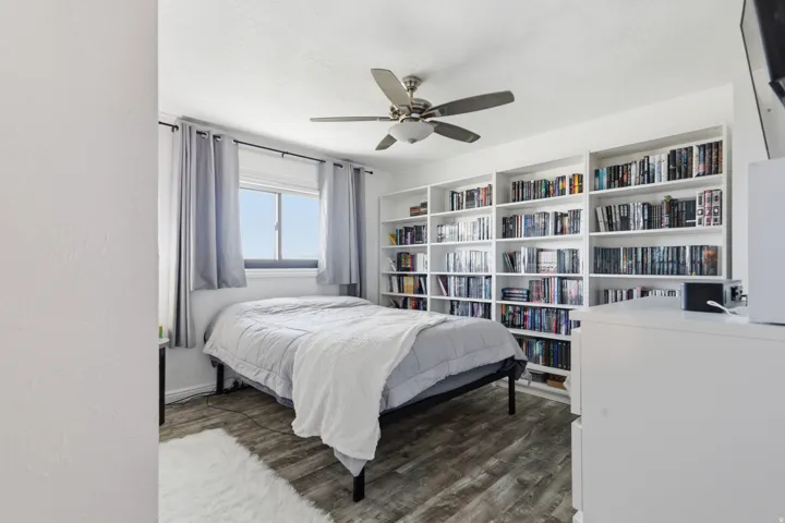 Bedroom with dark wood-type flooring, ceiling fan, and a textured ceiling