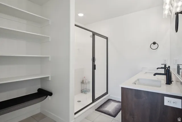 Full bathroom featuring a stall shower, double vanity, light tile patterned floors, recessed lighting, and a closet