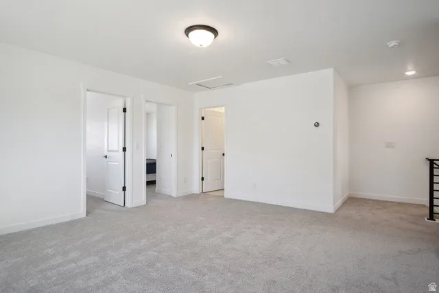 Unfurnished bedroom with light carpet and attic access