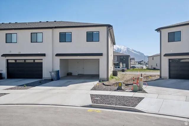 View of front facade featuring an attached garage, a mountain view, driveway, and stucco siding