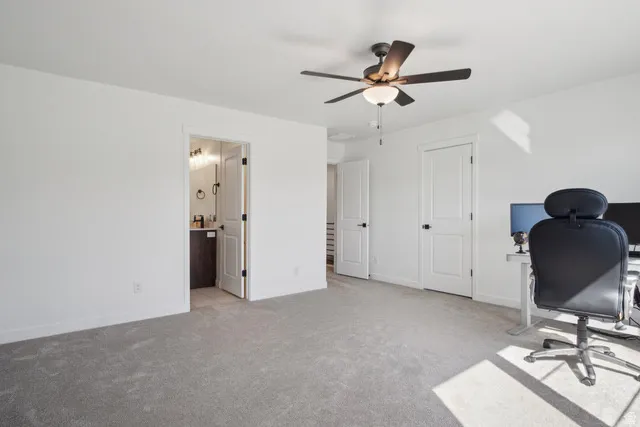 Office space with light carpet and ceiling fan
