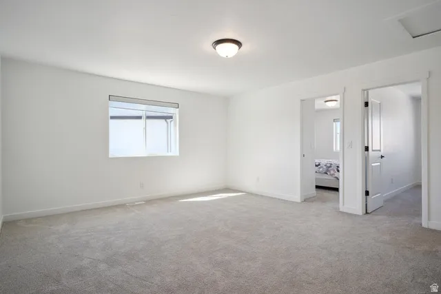 Unfurnished bedroom with light carpet and baseboards