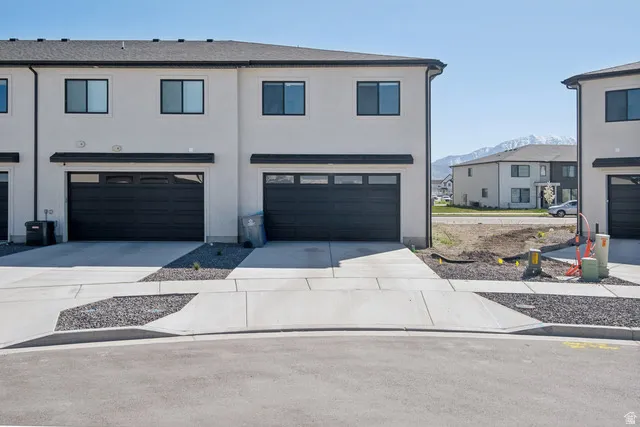 View of front of house featuring an attached garage, driveway, and stucco siding