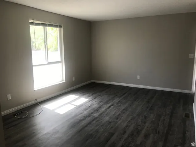 Empty room featuring dark wood finished floors and baseboards