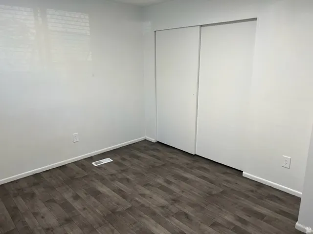Unfurnished bedroom with dark wood finished floors and a closet
