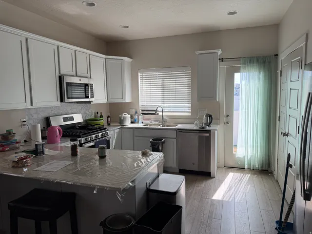 Kitchen with stainless steel appliances, a peninsula, white cabinets, a breakfast bar, and healthy amount of natural light