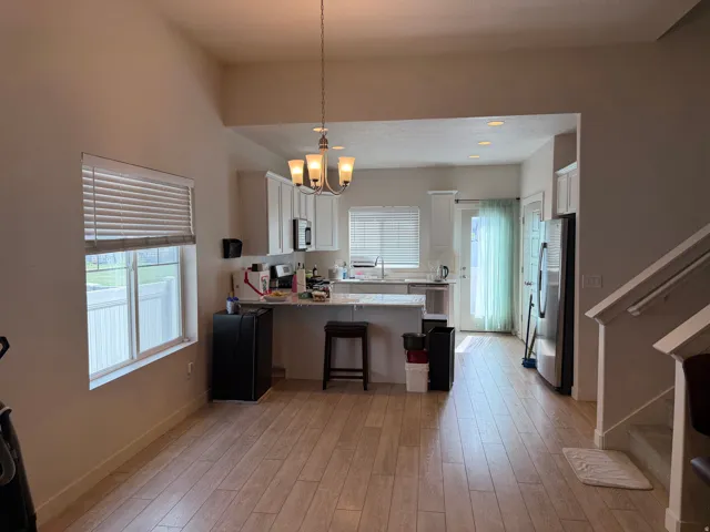 Kitchen with a peninsula, a kitchen breakfast bar, white cabinetry, stainless steel appliances, and hanging lights