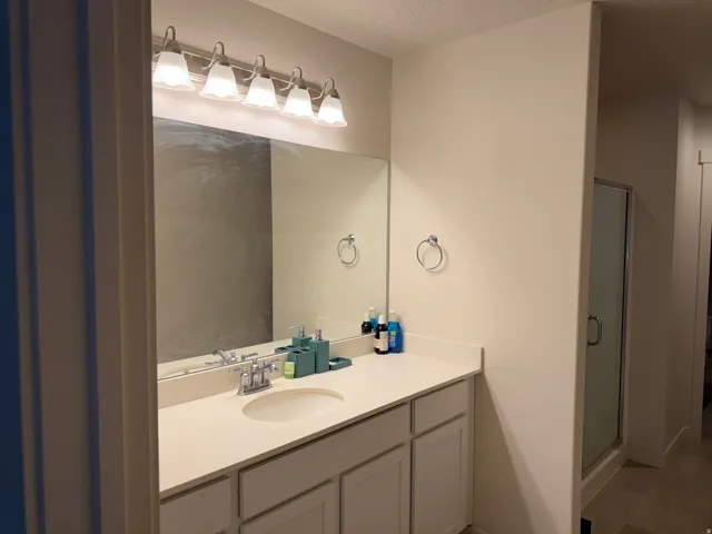 Full bath with vanity, a shower stall, and a textured ceiling