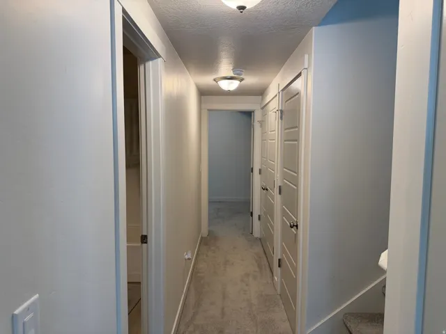 Hall with a textured ceiling and light colored carpet