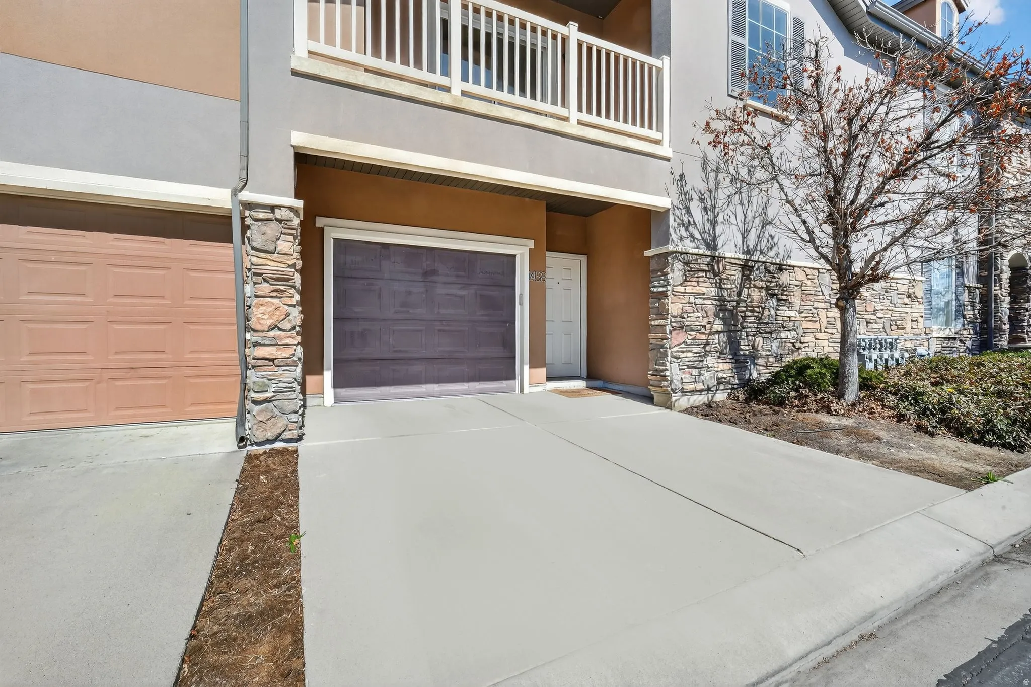 Property entrance featuring stone siding, stucco siding, driveway, and a garage