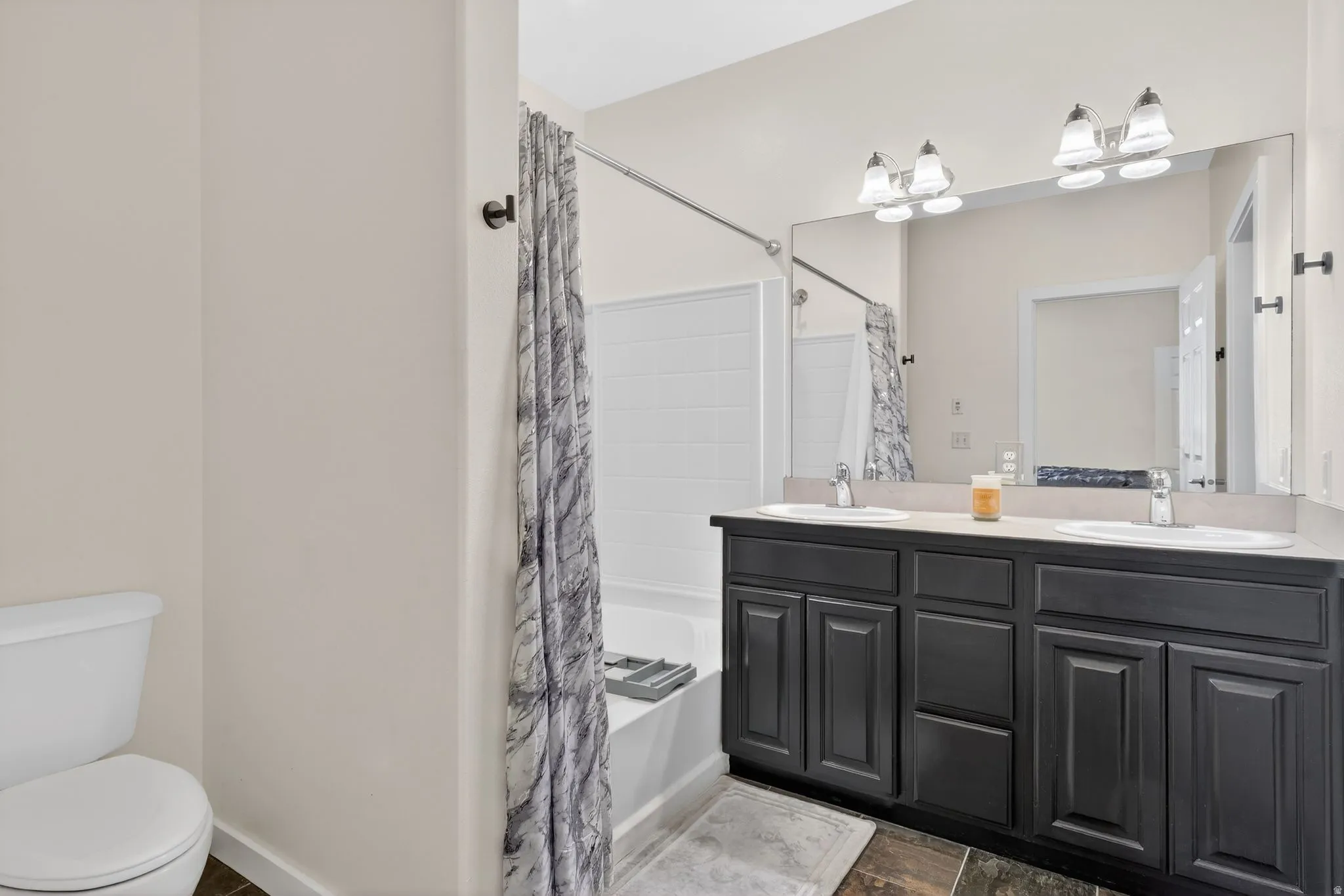 Bathroom with double vanity and shower / tub combo with curtain