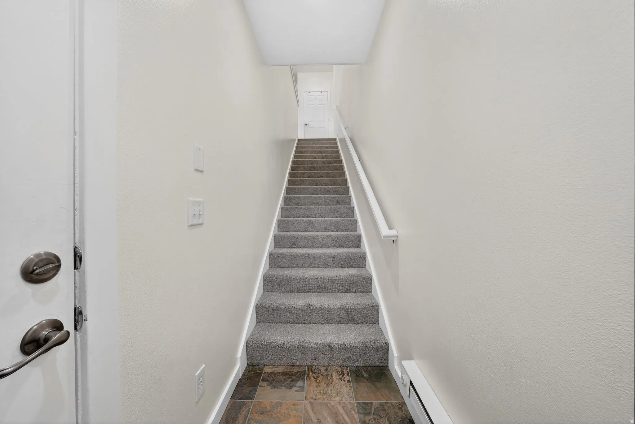 Stairs with stone finish floors and a baseboard heating unit