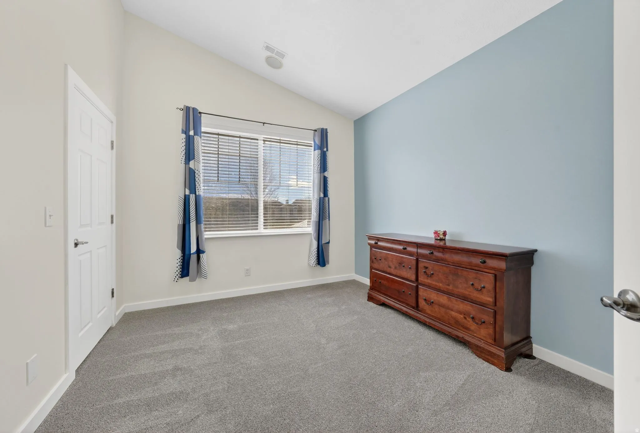 Bedroom with vaulted ceiling and light colored carpet