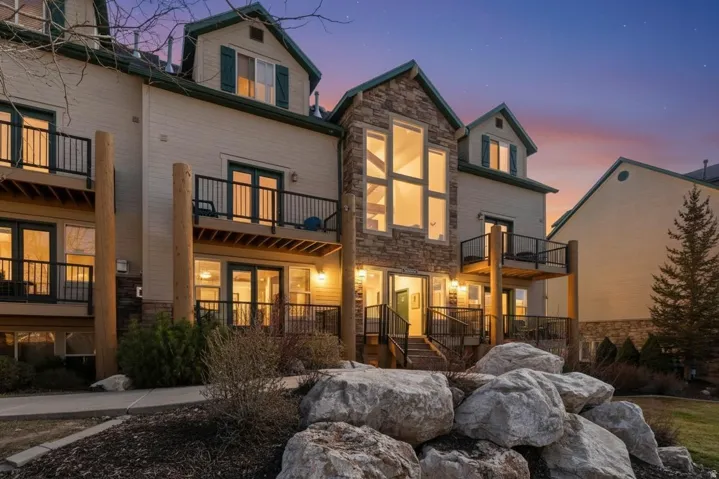 Rear view of house featuring stone siding and a balcony