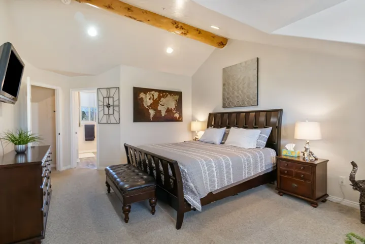Bedroom with vaulted ceiling with beams, light carpet, recessed lighting, and connected bathroom