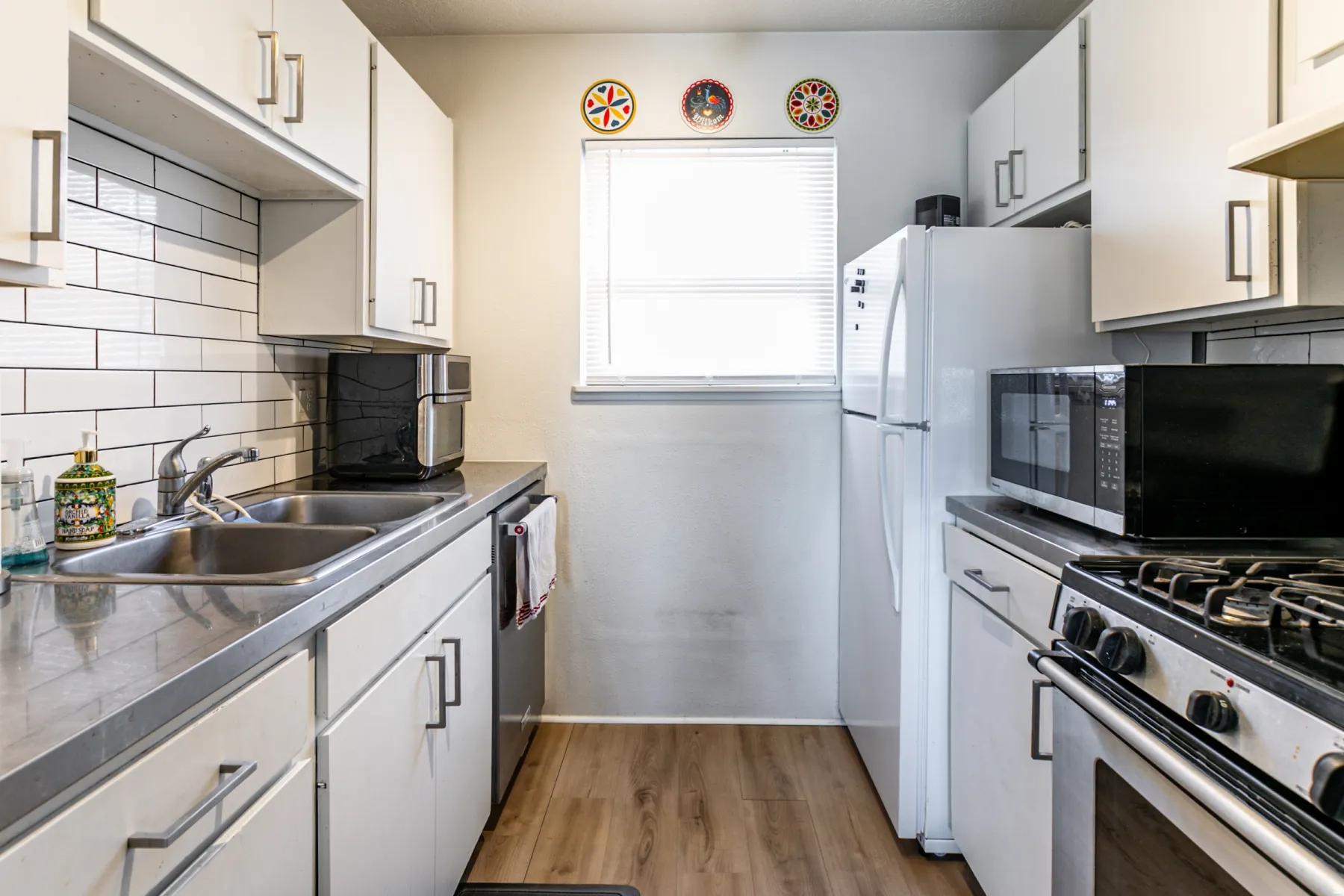 Kitchen featuring white cabinetry, backsplash, stainless steel appliances, and light wood-style floors