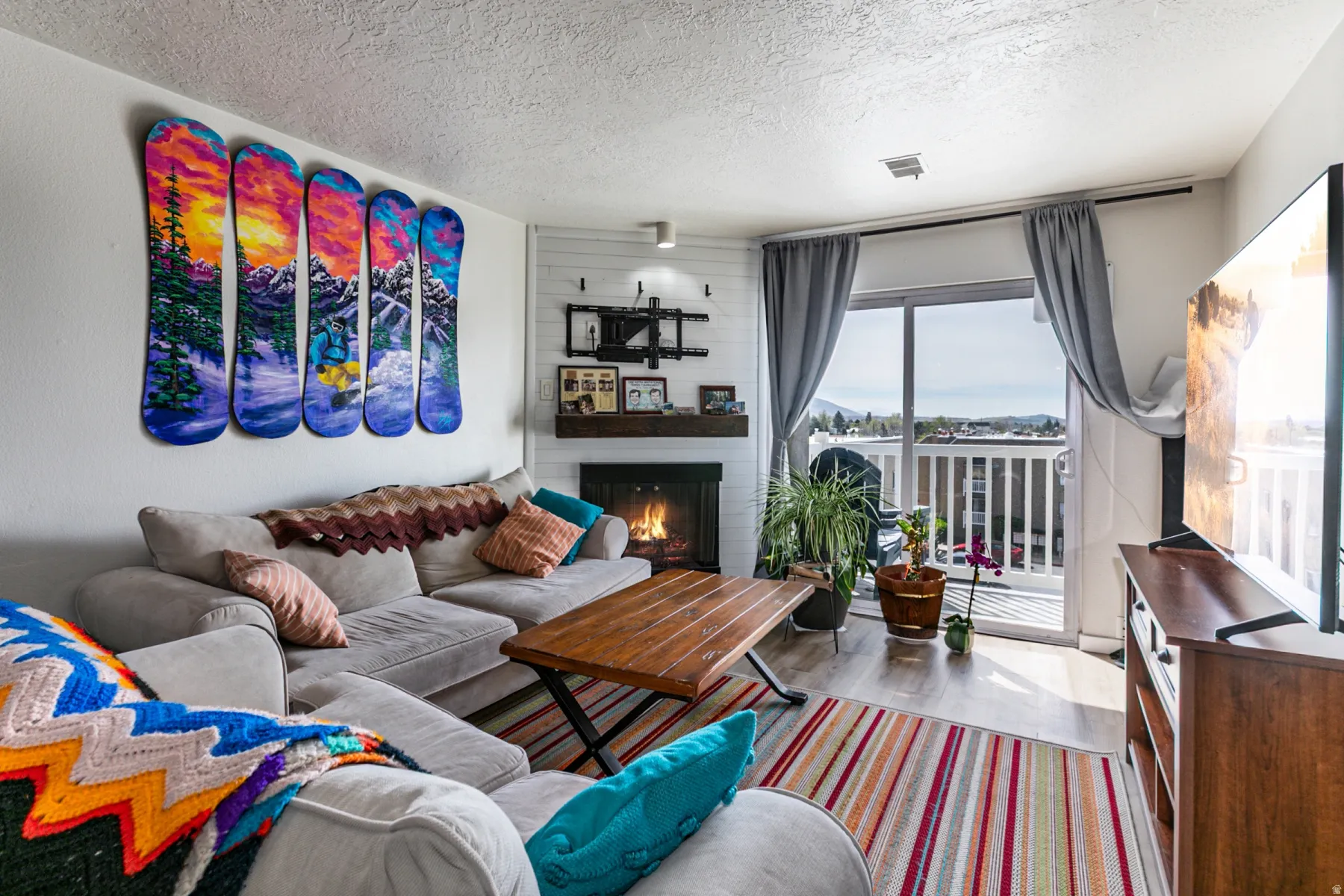 Living room with wood finished floors, a textured ceiling, and a large fireplace