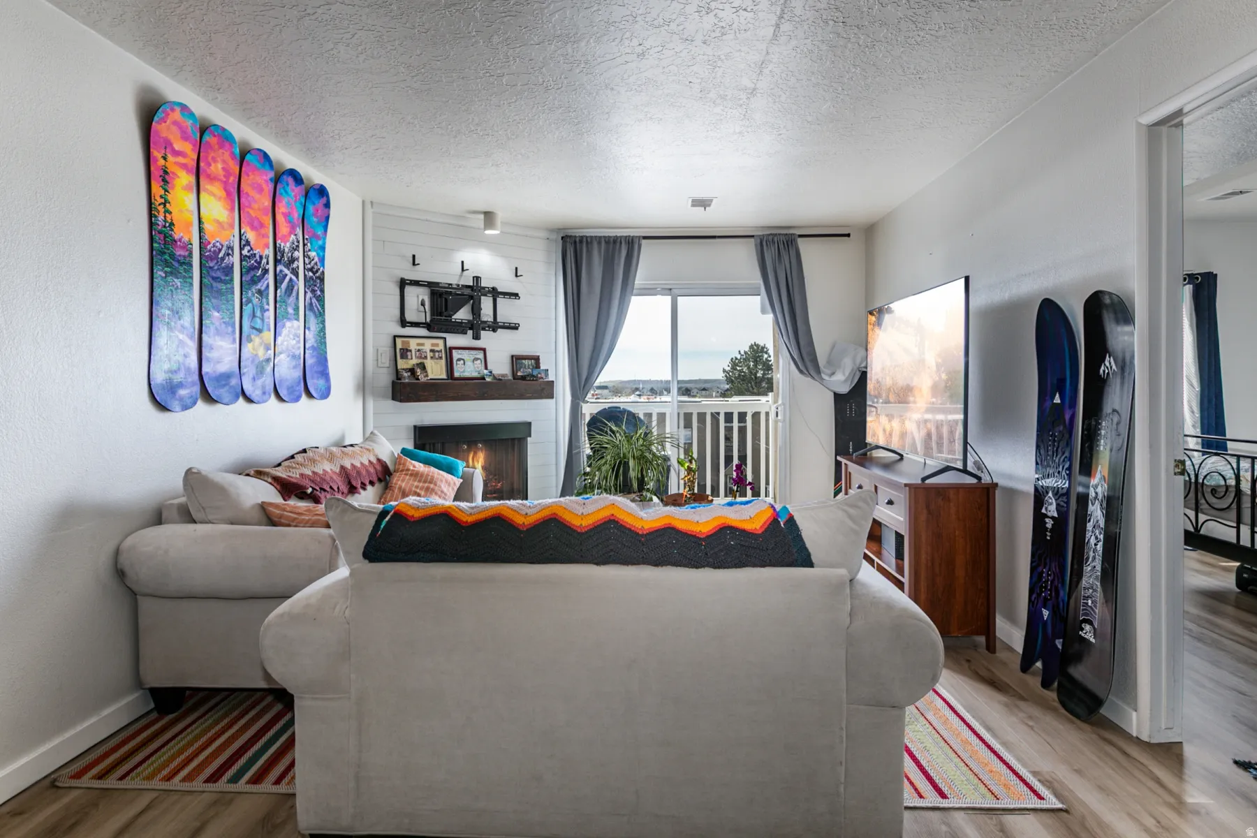 Living room with a large fireplace, a textured ceiling, and light wood-style floors