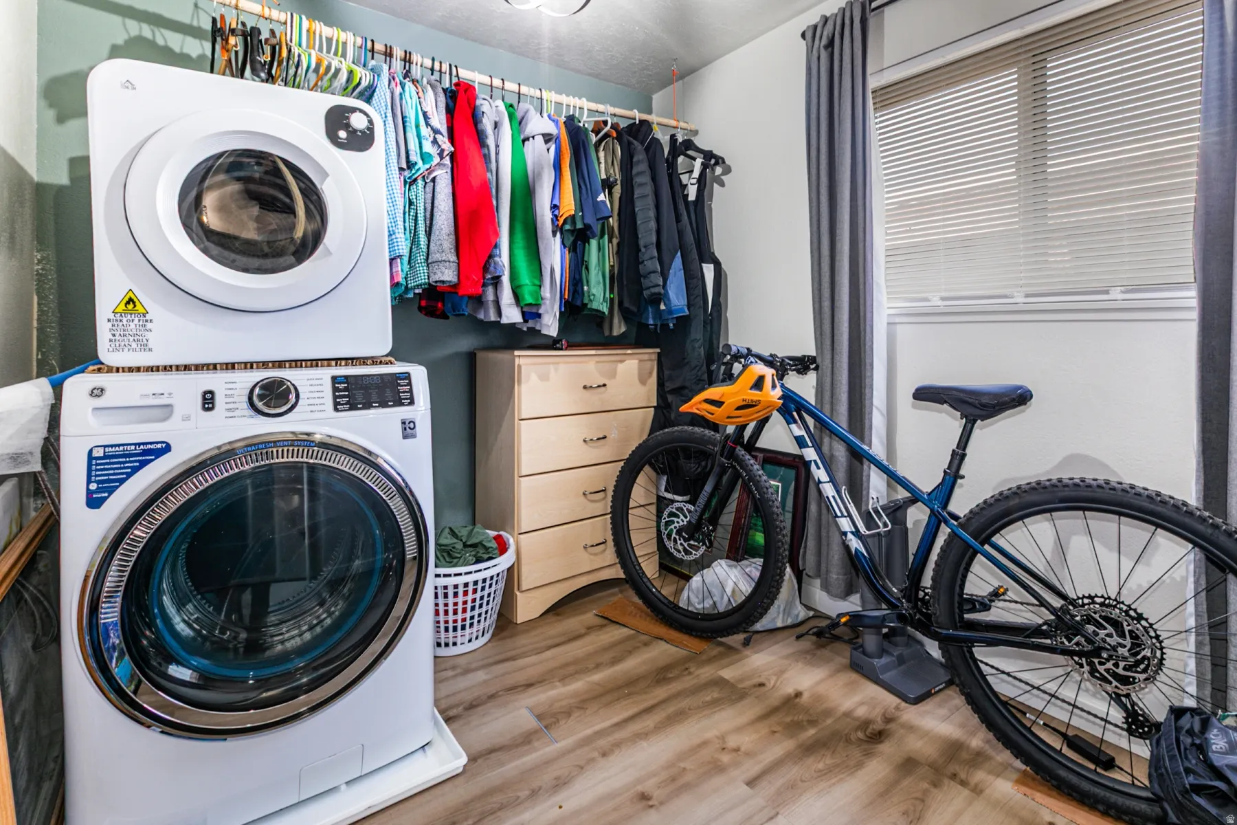 Laundry area with stacked washing machine and dryer and light wood finished floors