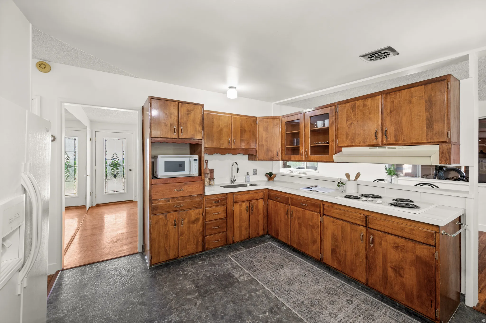 Kitchen featuring light countertops, wood finish cabinetry, and white appliances