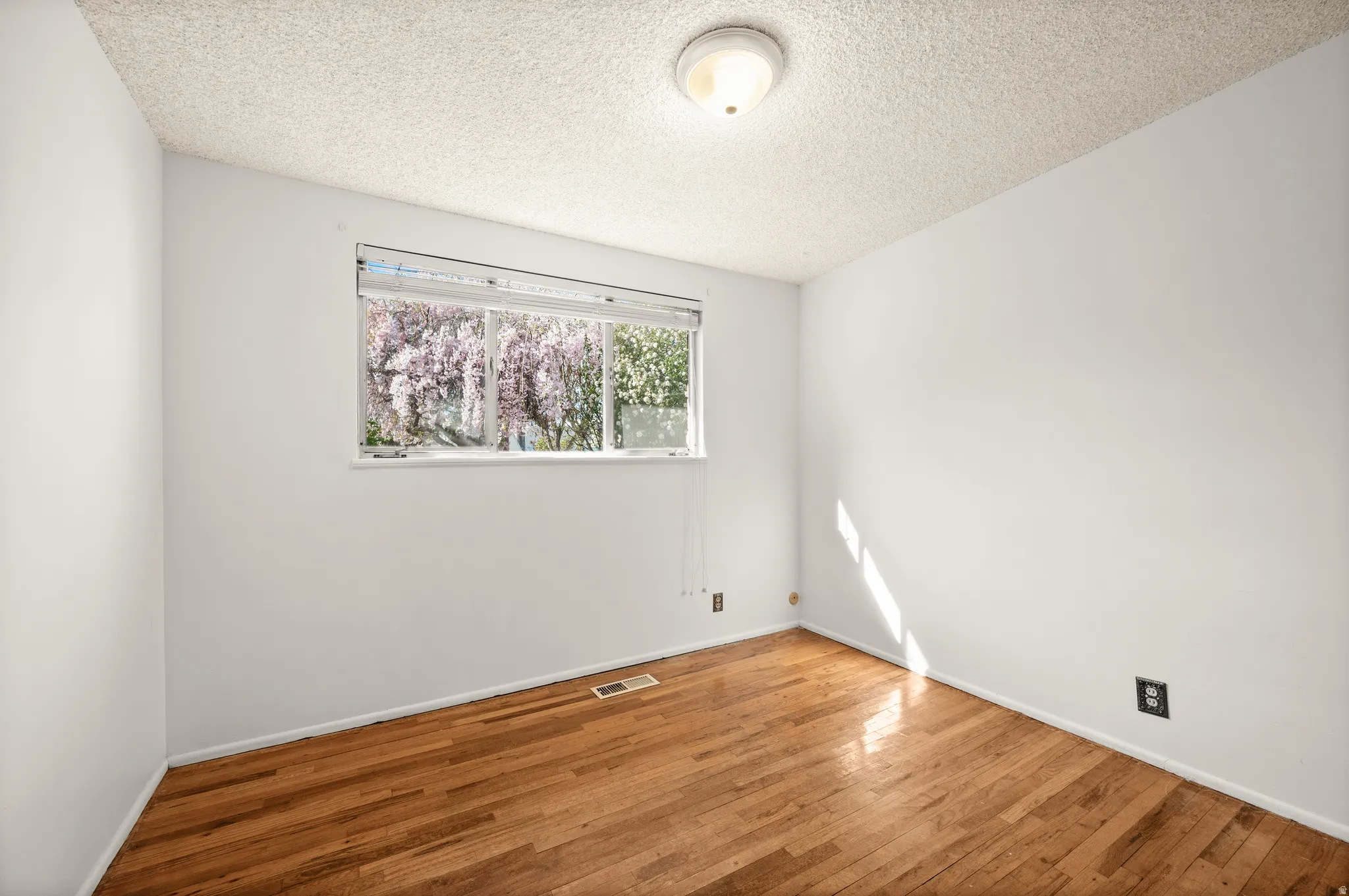 Empty room with hardwood / wood-style floors and a textured ceiling