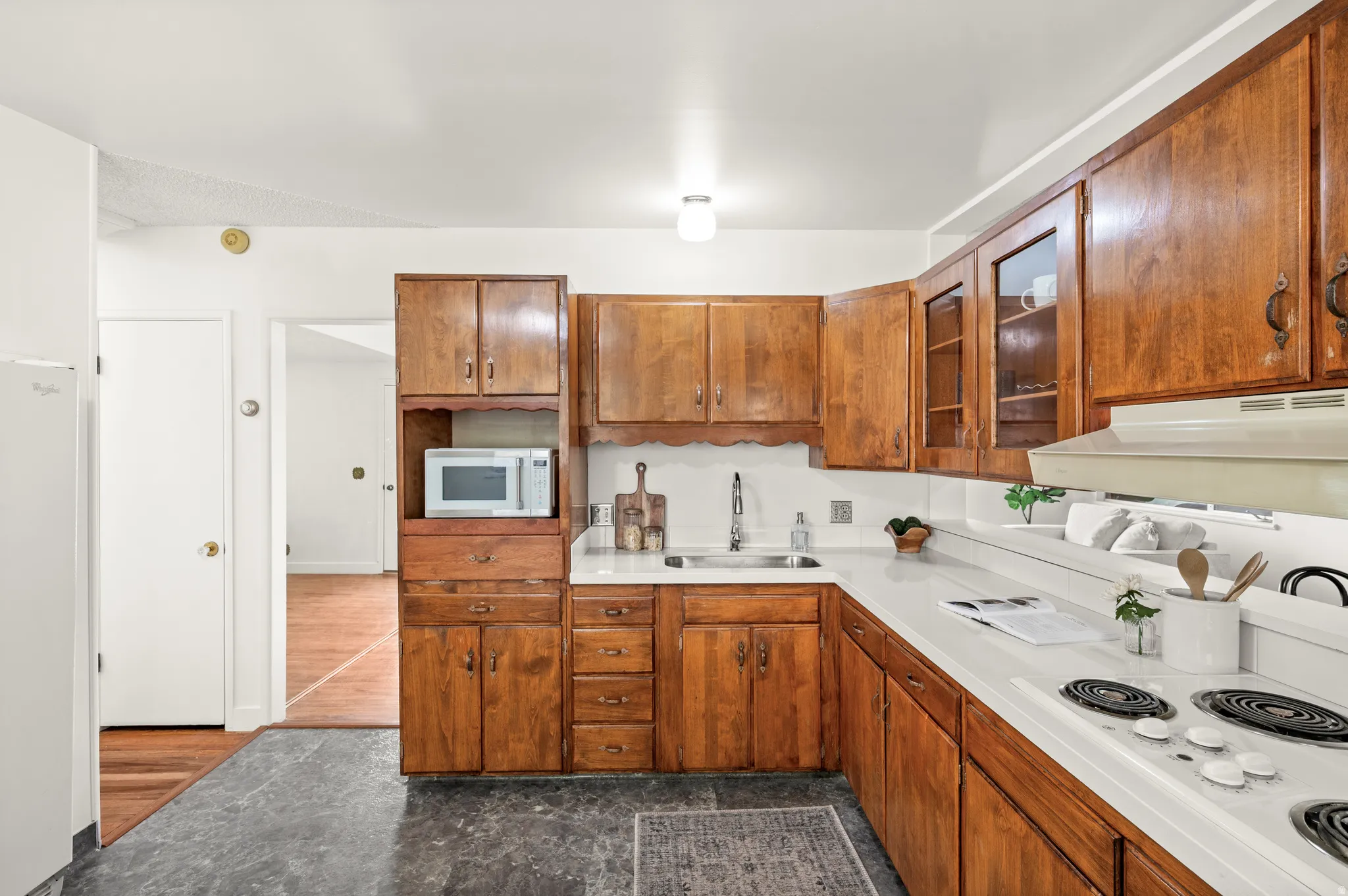 Kitchen with wood finish cabinetry, light countertops, and white appliances