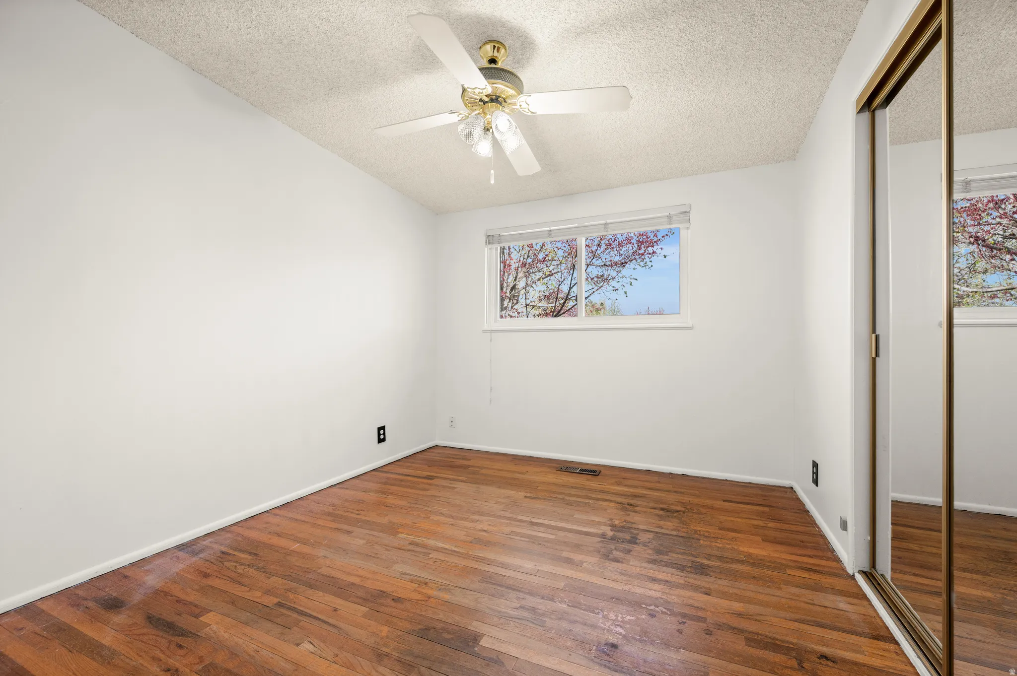 Unfurnished bedroom featuring a closet, dark wood-style floors, ceiling fan, and a textured ceiling
