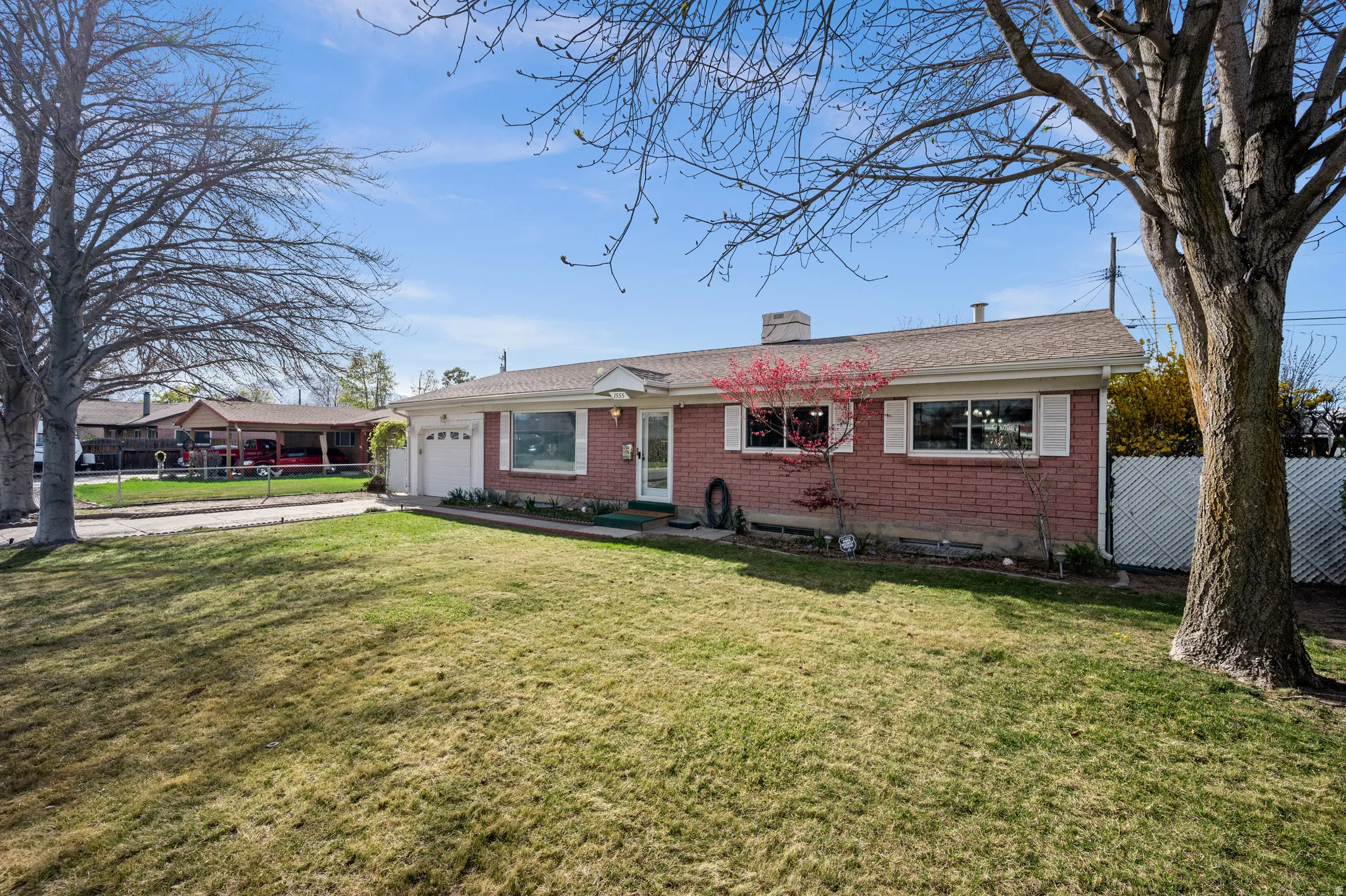 Ranch-style home featuring brick siding, an attached garage, driveway, and a chimney