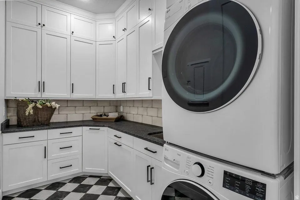 Laundry area featuring dark floors, cabinet space, and stacked washer and clothes dryer